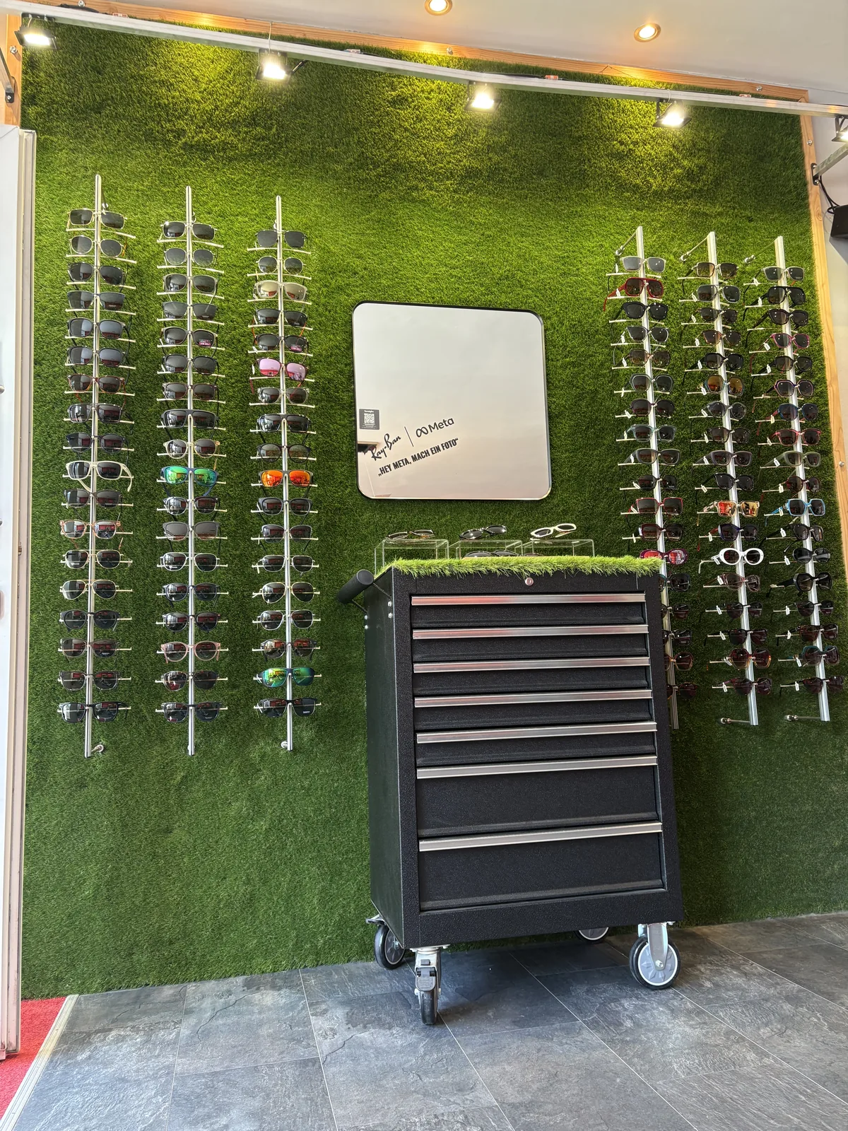 Sonnenbrillen an einer Wand aus Kunstrasen bei die sichtbar